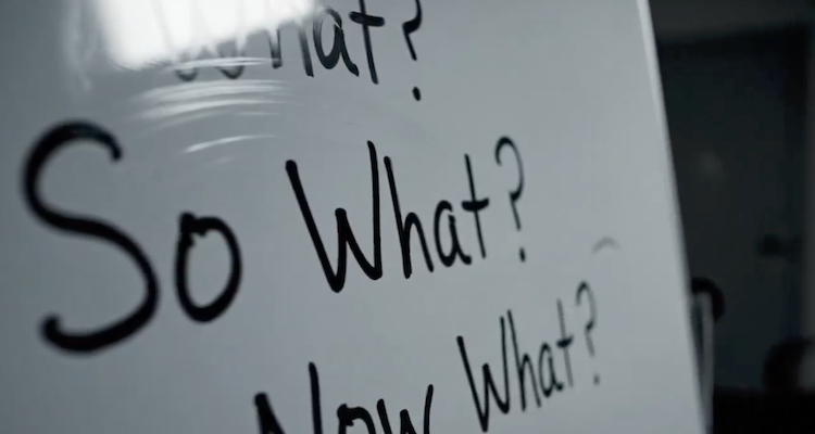A whiteboard featuring the handwritten questions "What? So What? Now What?" in a modern office setting. This visual represents a strategic framework used by advisory boards and executives to move from raw data to actionable insights and forward-looking governance.