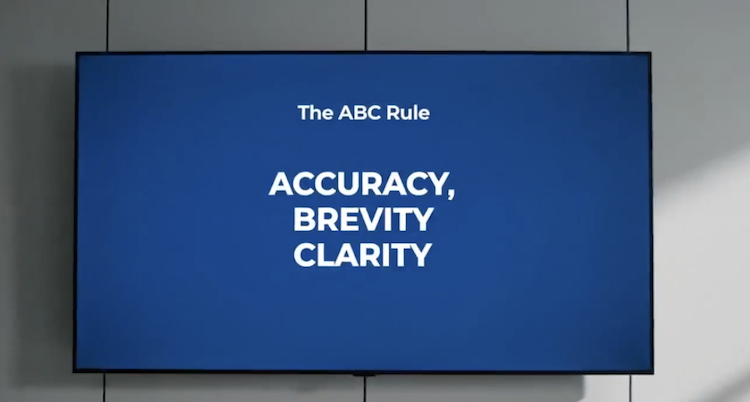 A digital display in a modern office showing "The ABC Rule" with the words "ACCURACY, BREVITY, CLARITY." This visual represents the gold standard for board papers and executive reporting, illustrating how high-quality information flow enables effective advisory board governance and decision-making.